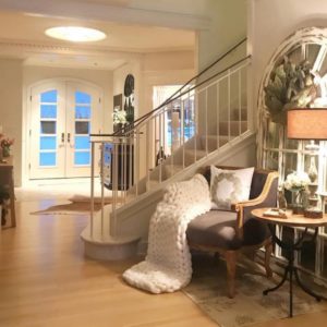 Farmhouse entryway way with a gray accent chair and white knit blanket.