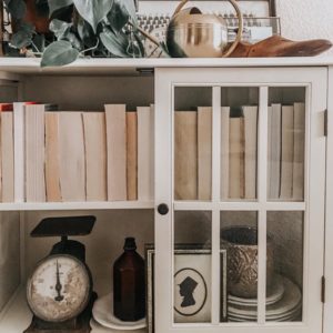 White shelf with vintage books and antique decor.