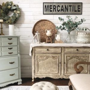 Dining room with shiplap walls, a gray dresser and brown rustic buffet. Gorgeous farmhouse home decor, white pitchers,farmhouse white rug and magnolia wreath.